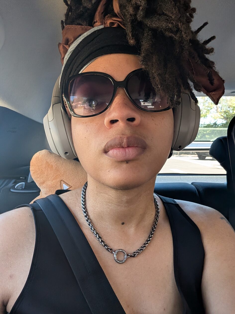 Kai wearing sunglasses and headphones in a car